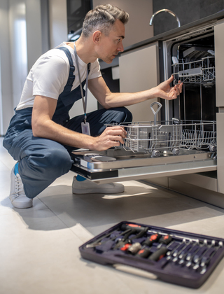 Profile of man crouching looking into open dishwasher